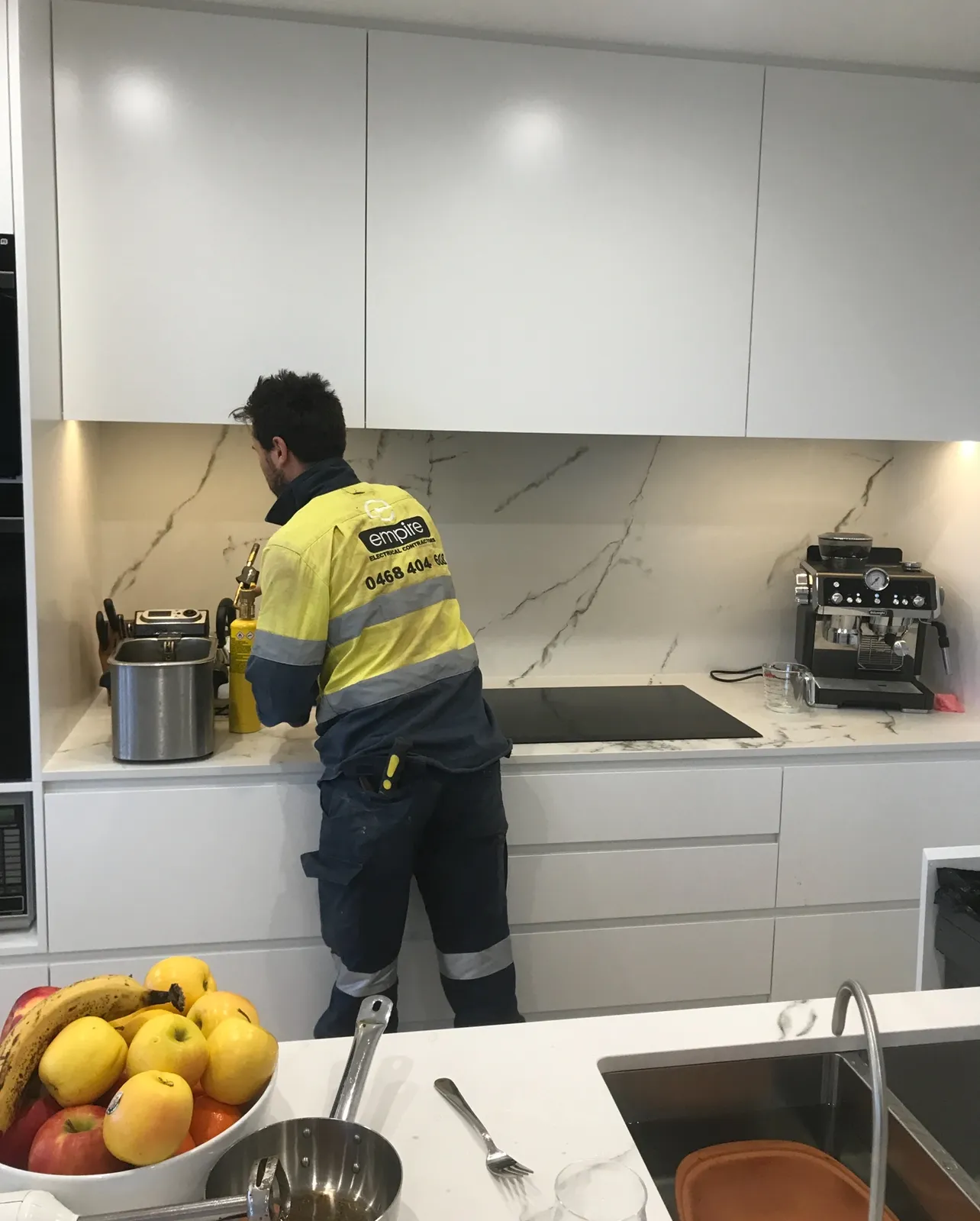 Empire electrician working on a kitchen cooktop install in Sydney